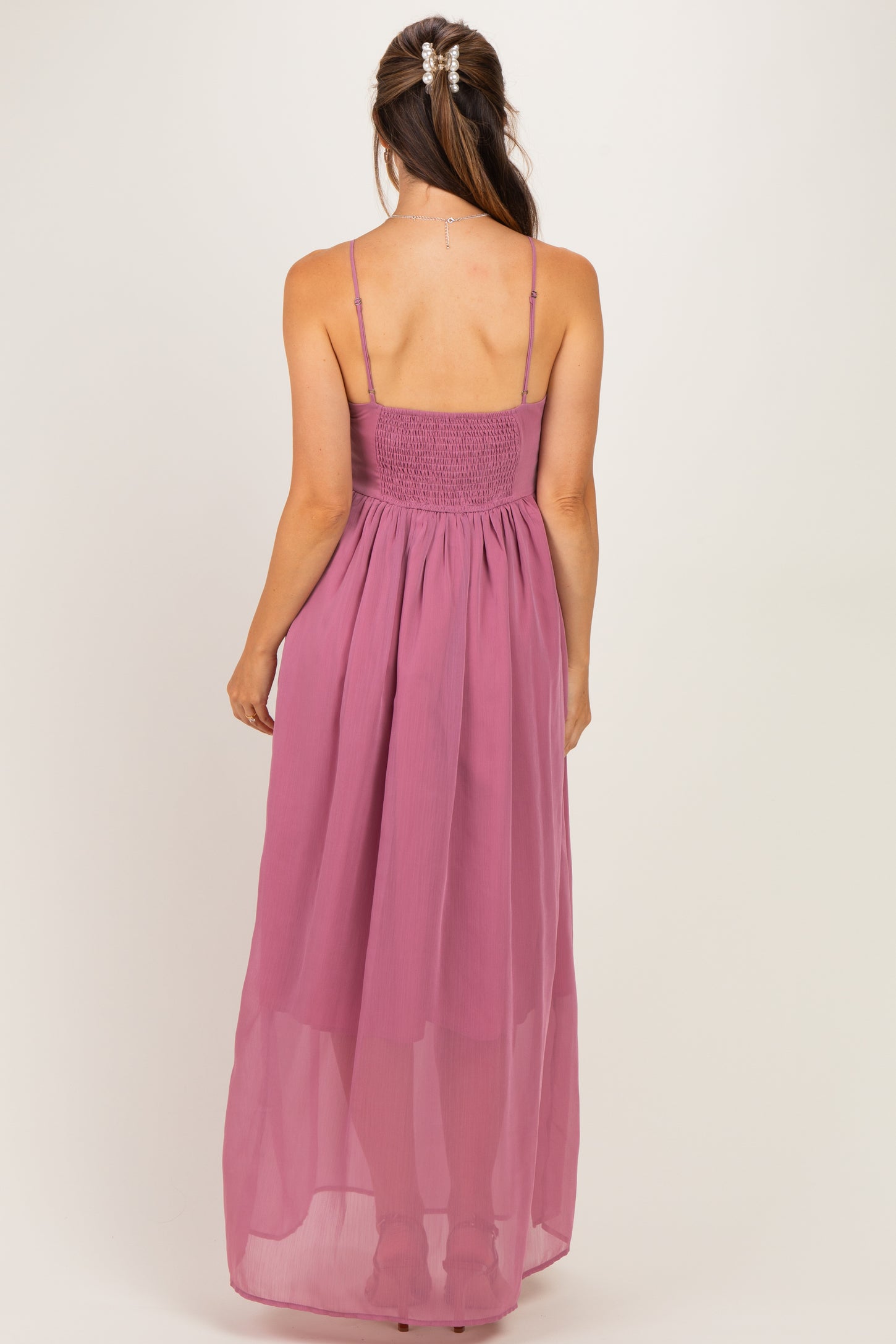 woman wearing a mauve maternity maxi dress with a smocked bodice and sheer skirt, seen from the back