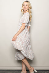 woman wearing a floral print midi dress with short ruffled sleeves and a flowing skirt