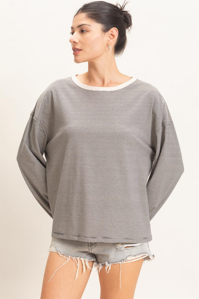 woman wearing a gray and white striped oversized sweatshirt with rolled cuffs and distressed denim shorts