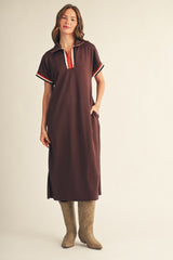 woman wearing a brown midi dress with a collar and striped details, paired with tan cowboy boots and standing with hands in pockets