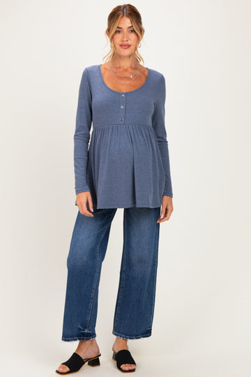 woman wearing a blue maternity long sleeve top with buttons and a baby bump, paired with wide-leg jeans