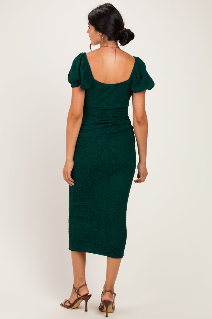 woman wearing a green fitted midi dress with puff sleeves and a ruched design, viewed from the back