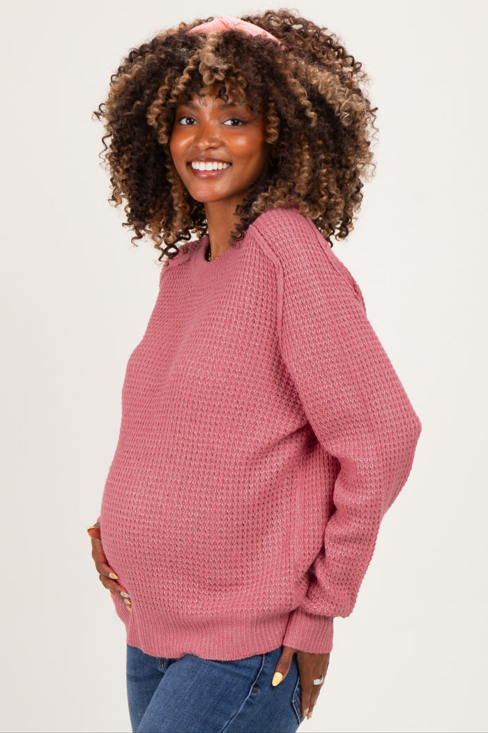 woman wearing a pink textured maternity sweater and showing her baby bump