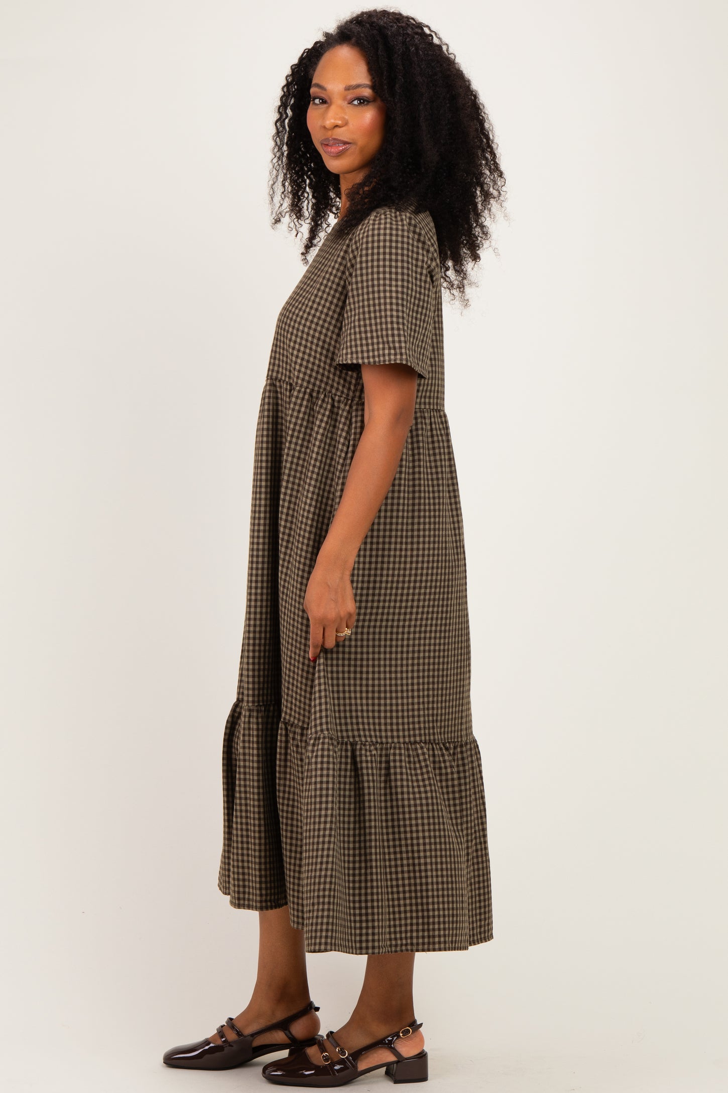 woman wearing a brown and black checkered midi dress with short sleeves and ruffled hem