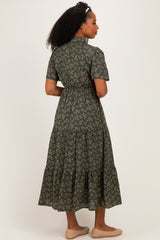 woman wearing a dark green floral maxi dress with short sleeves and a tiered skirt, seen from the back