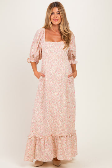 woman wearing a pink floral maternity maxi dress with puff sleeves and side pockets