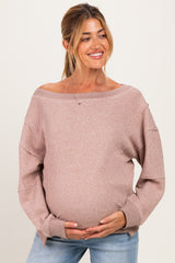 woman wearing a light pink off-shoulder maternity sweater and holding her baby bump