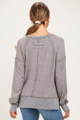 woman wearing a gray striped long sleeve maternity top, showing the back view with ribbed details