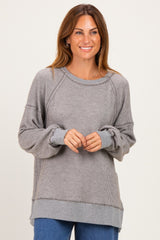 woman wearing a gray striped long sleeve sweater with a relaxed fit and ribbed details, smiling at the camera