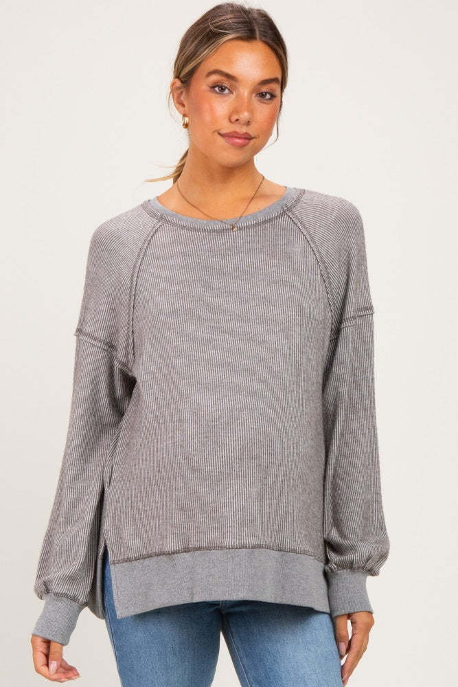 woman wearing a gray striped maternity sweater with long sleeves and side slits, styled with blue jeans