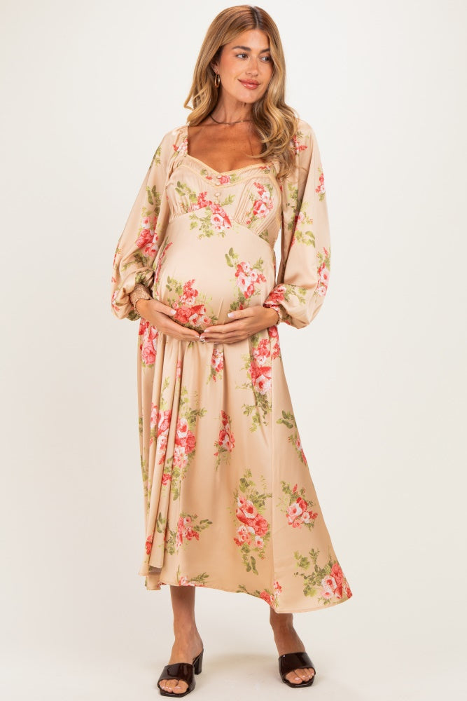 woman wearing a floral print beige maternity dress with puff sleeves and holding her baby bump