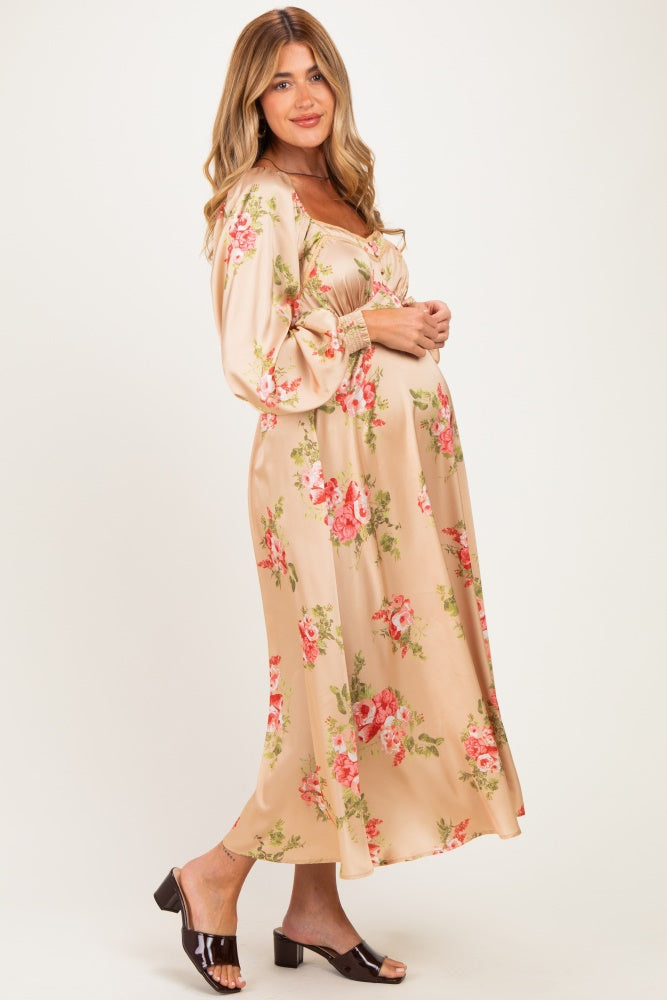 woman wearing a floral satin maternity dress with balloon sleeves and a visible baby bump