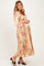 woman wearing a floral satin maternity dress with balloon sleeves and a visible baby bump
