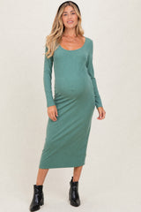 woman wearing a green long sleeve ribbed maternity dress and showing her baby bump