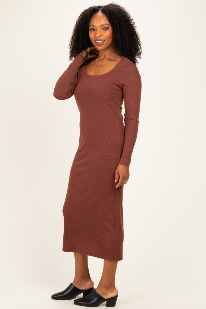 woman wearing a rust brown long sleeve ribbed maxi dress and black mules, posing with one hand on her shoulder