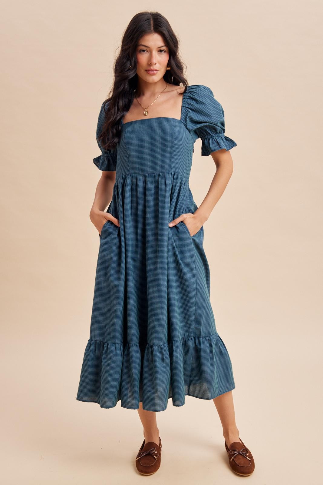 woman wearing a blue puff sleeve maxi dress with a square neckline and pockets, styled with a ruffled hemline