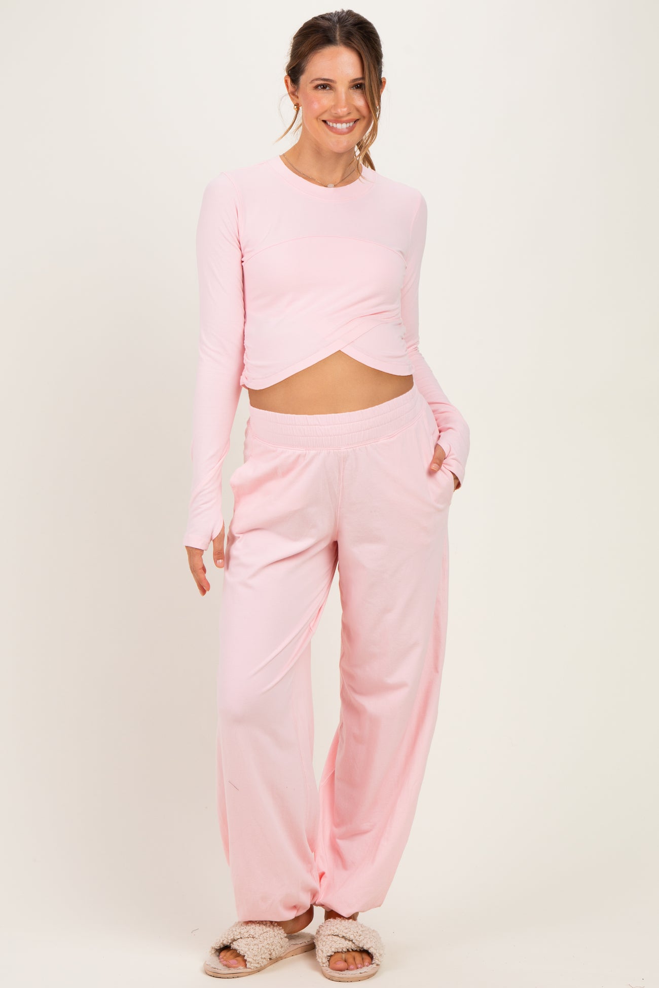 woman wearing a light pink long sleeve maternity top with a knot detail and matching relaxed fit pants