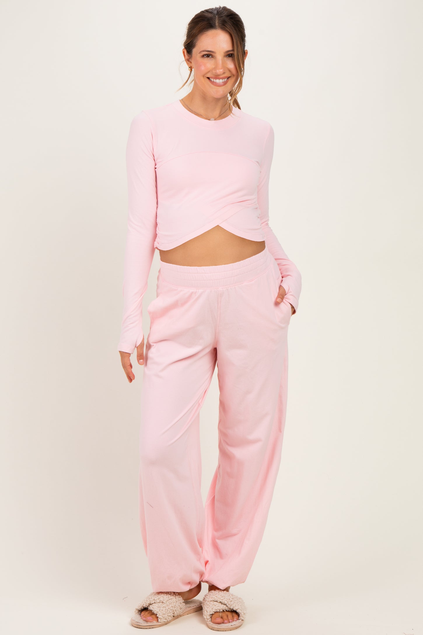 woman wearing a light pink long sleeve maternity top with a knot detail and matching relaxed fit pants