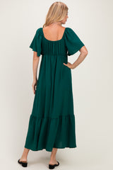 woman wearing a green maxi dress with short flutter sleeves and a tiered skirt, shown from the back