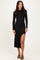 woman wearing a black long sleeve midi dress with a side slit and strappy sandals