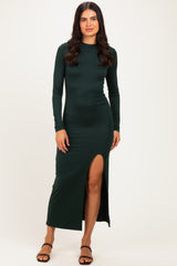 woman wearing a dark green long sleeve maxi dress with a side slit and strappy sandals