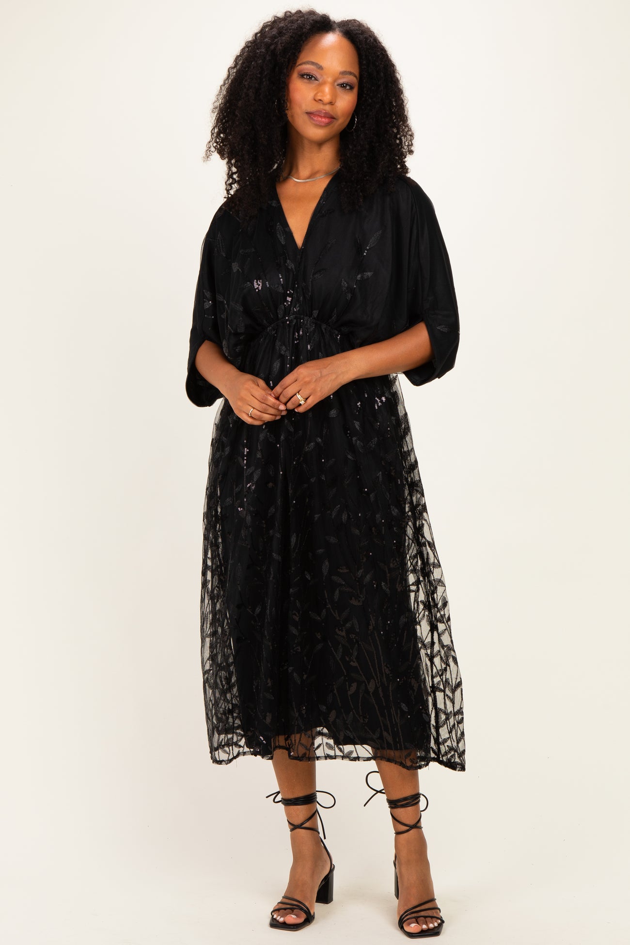 woman wearing a black embroidered midi dress with a tie waist detail and short sleeves