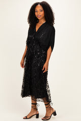 woman wearing a black floral lace midi dress with short sleeves and a fitted waist, paired with strappy black heels