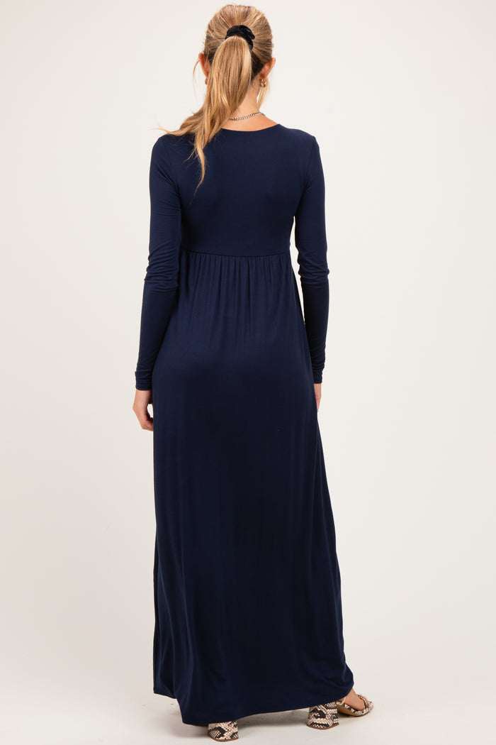 woman wearing a long sleeve navy blue maternity maxi dress with a fitted bodice and flowing skirt