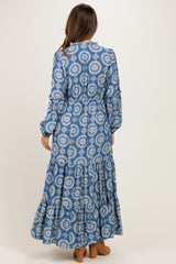 woman wearing a blue floral maternity maxi dress with long sleeves and tiered skirt, seen from the back
