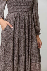 woman wearing a brown floral smocked maxi dress with long sleeves and pockets