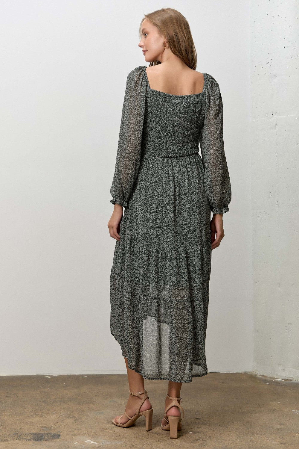 woman wearing a dark green floral midi dress with long sleeves and a square neckline, viewed from the back