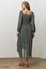 woman wearing a dark green floral midi dress with long sleeves and a square neckline, viewed from the back