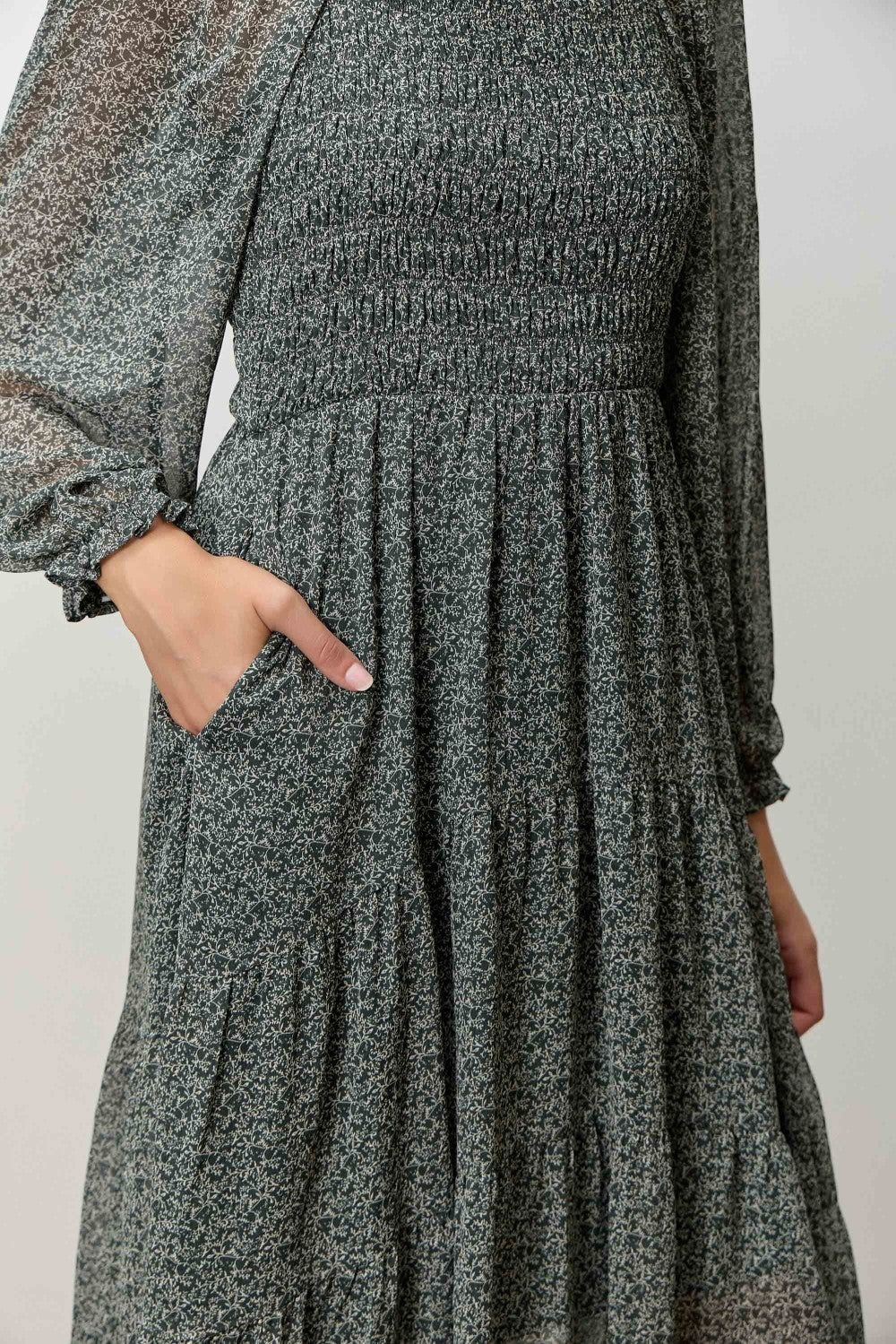 woman wearing a green floral smocked maxi dress with long sleeves and pockets