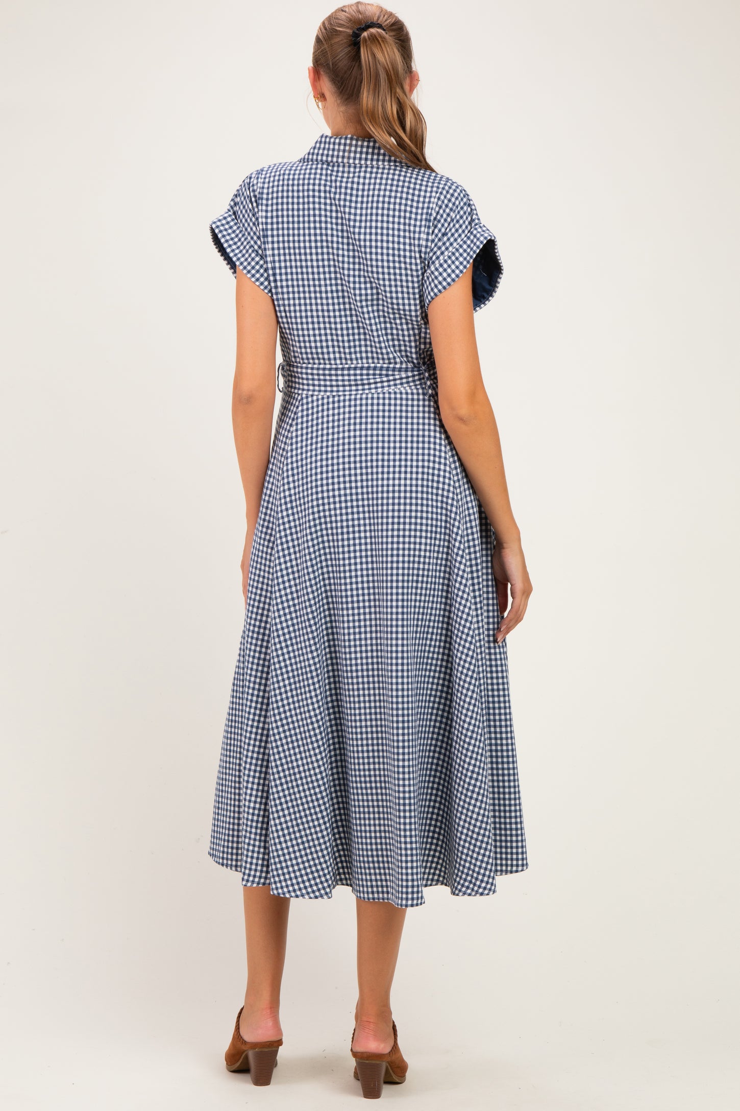 woman wearing a blue and white gingham maternity dress with short sleeves and a tie waist detailing