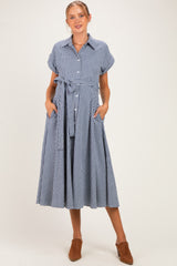woman wearing a blue and white checkered maternity dress with a tie waist and short sleeves, showing a baby bump