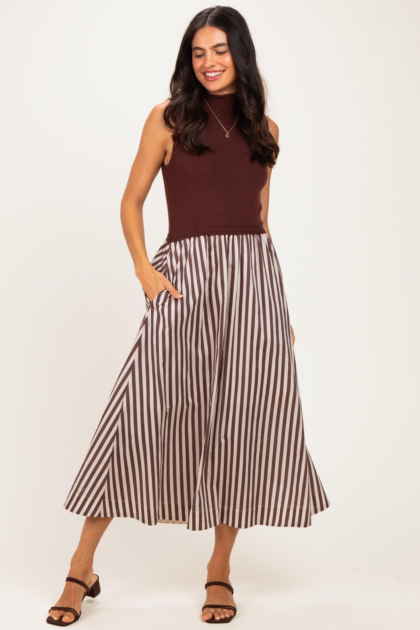 woman wearing a maroon sleeveless top and a striped midi skirt with pockets