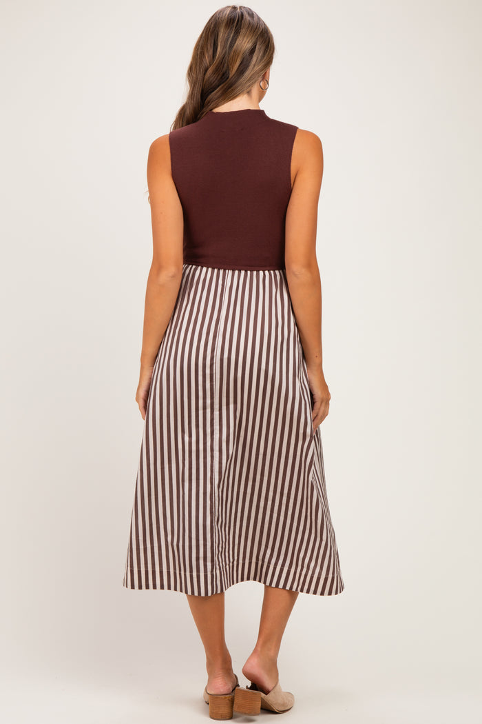 woman wearing a burgundy sleeveless maternity dress with a striped skirt, showing her back and a flowing silhouette