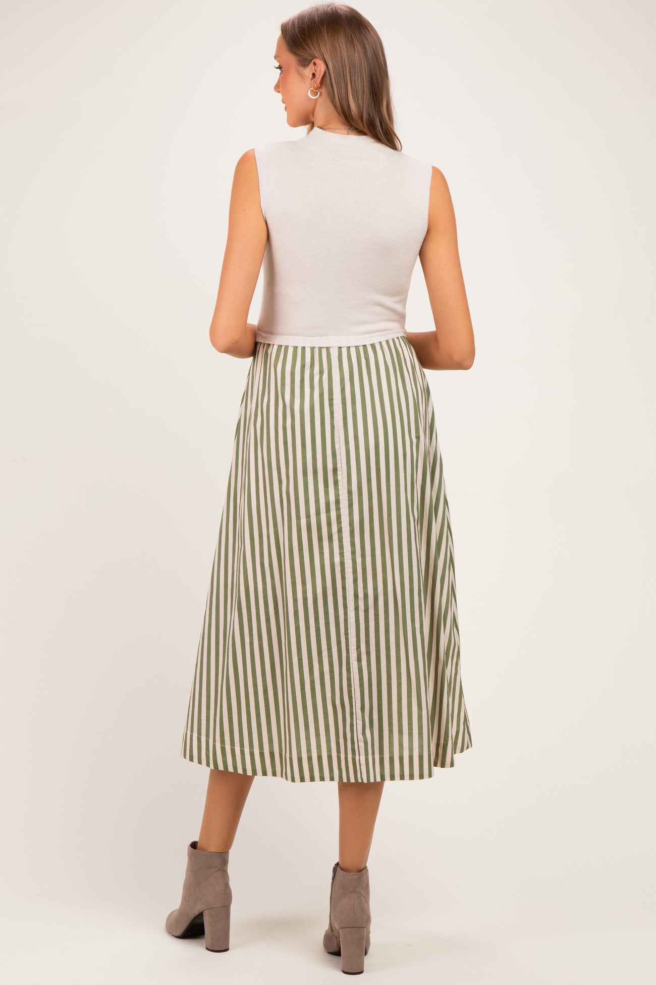 woman wearing a sleeveless white top and a green and white striped maternity maxi skirt, showing a baby bump from behind