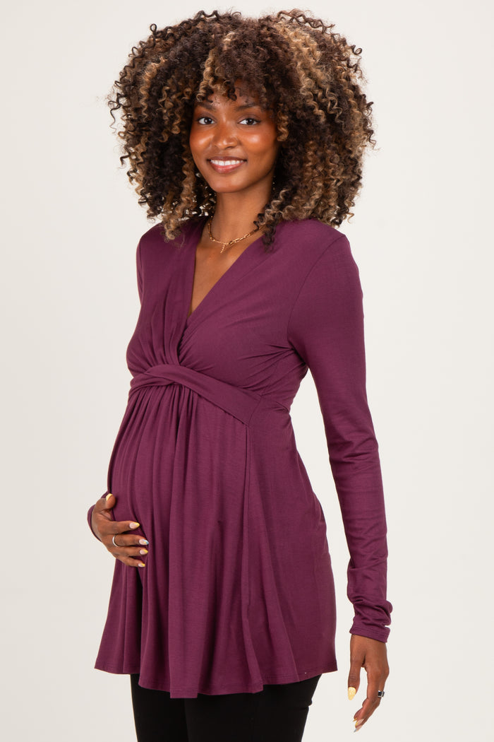 woman wearing a purple long sleeve maternity top and holding her baby bump