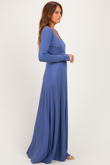 woman wearing a blue long sleeve maxi dress, standing in profile with a flowing silhouette