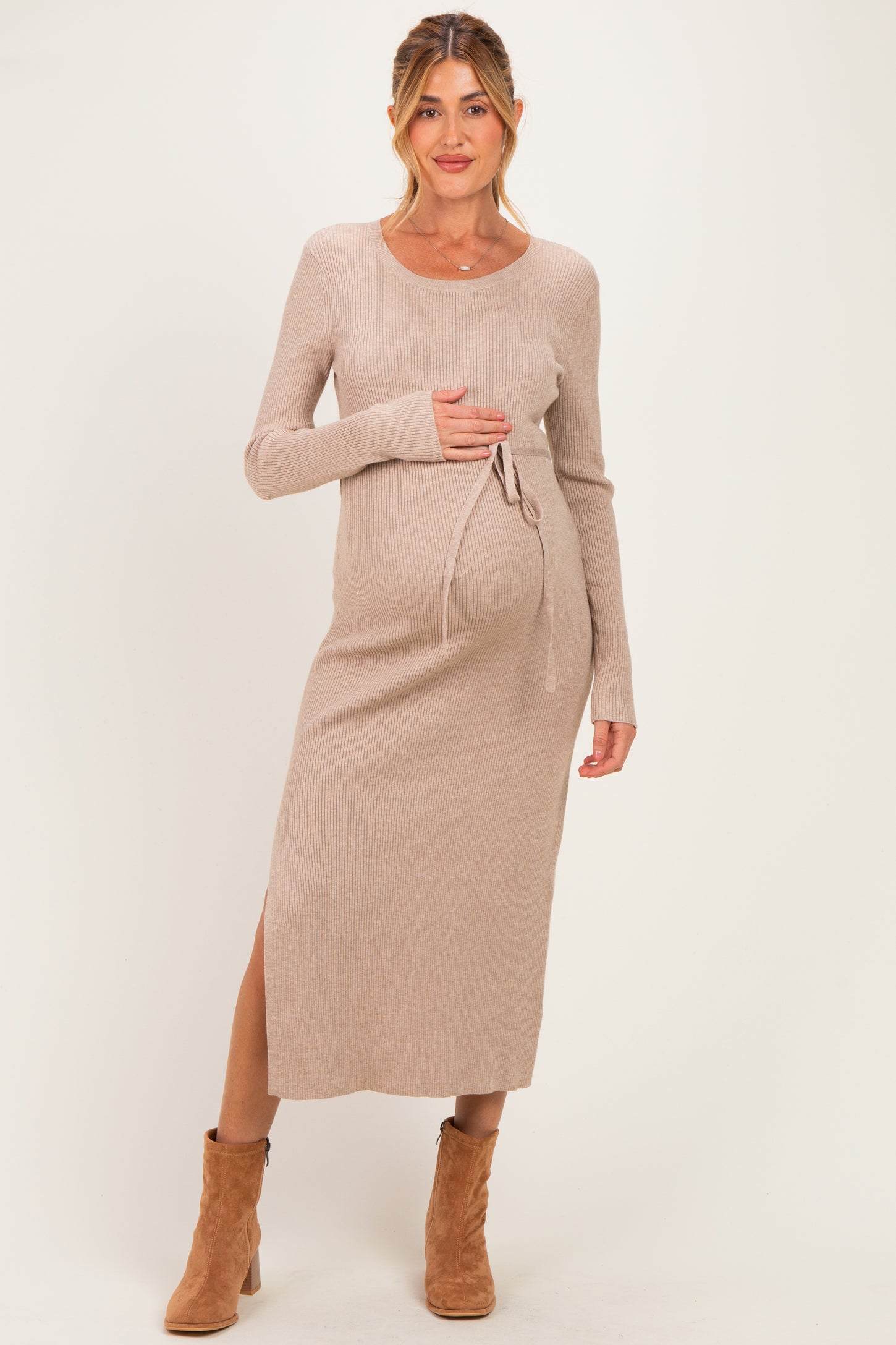 woman wearing a beige ribbed maternity dress with a side slit and tie detail, showcasing her baby bump