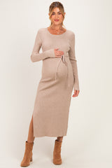 woman wearing a beige ribbed maternity dress with a side slit and tie detail, showcasing her baby bump
