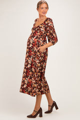 woman wearing a floral print maternity dress with pockets and three-quarter sleeves, showing her baby bump