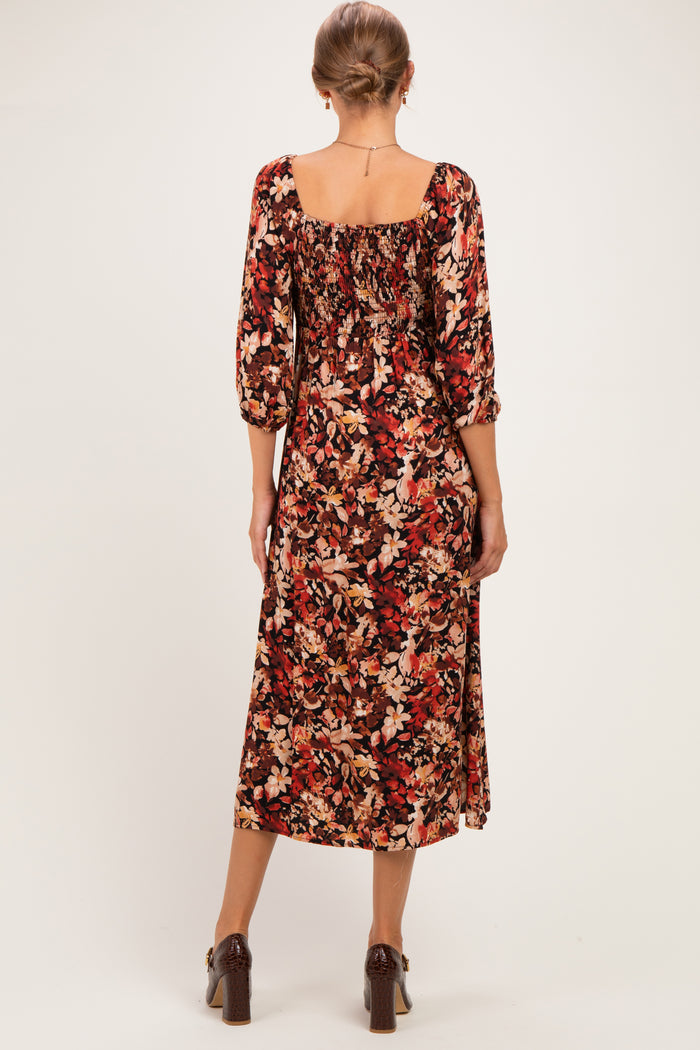 woman wearing a floral print maternity dress with three-quarter sleeves and a square neckline, showing a baby bump