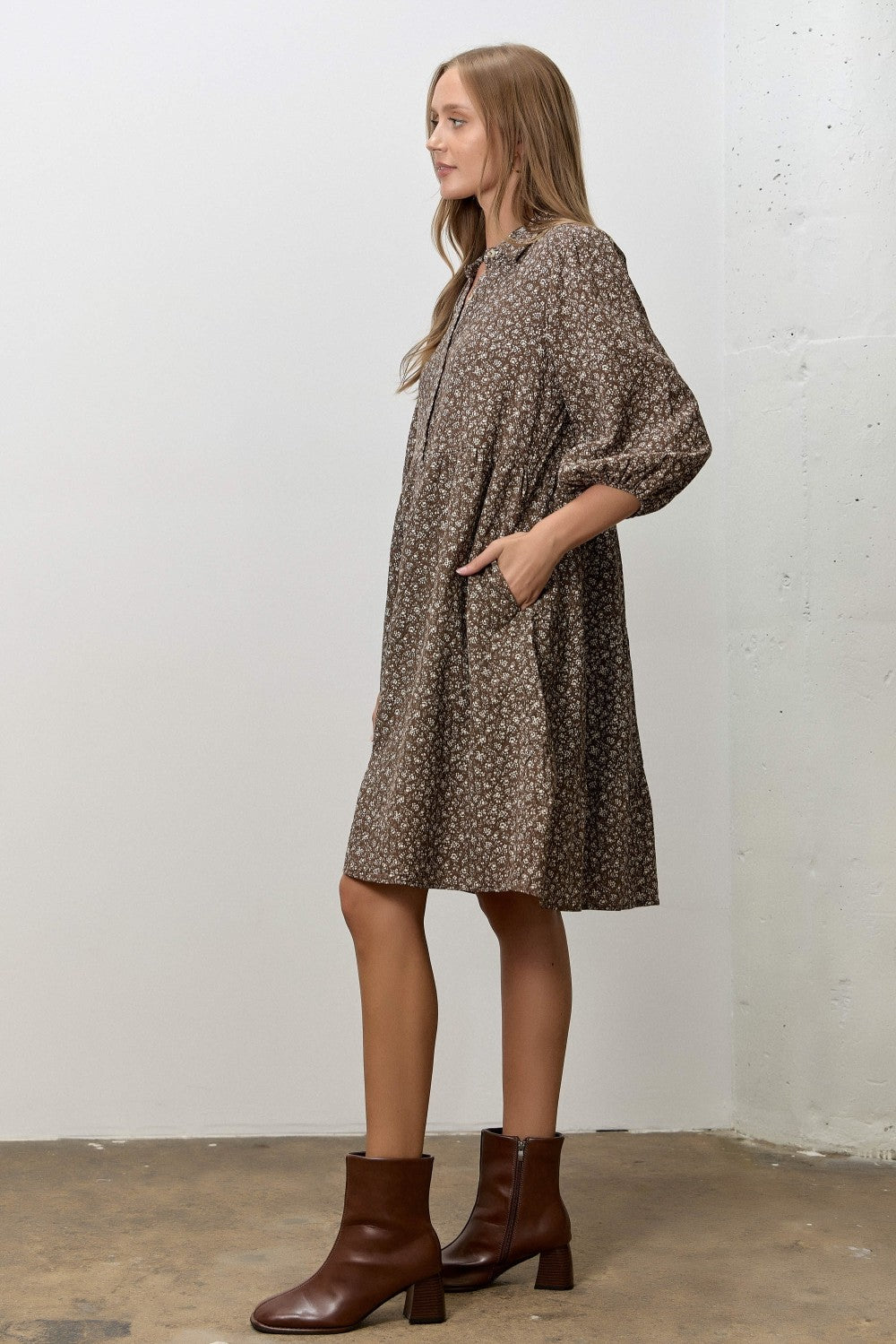 woman wearing a brown floral print midi dress with pockets and long sleeves, styled with brown ankle boots
