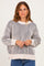 woman wearing a cream and navy striped oversized sweater with ribbed detailing and dropped shoulders