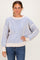 woman wearing a striped light blue and beige oversized sweater with balloon sleeves and casual blue jeans