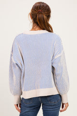 woman wearing a cream and blue striped oversized sweater paired with blue jeans, seen from the back