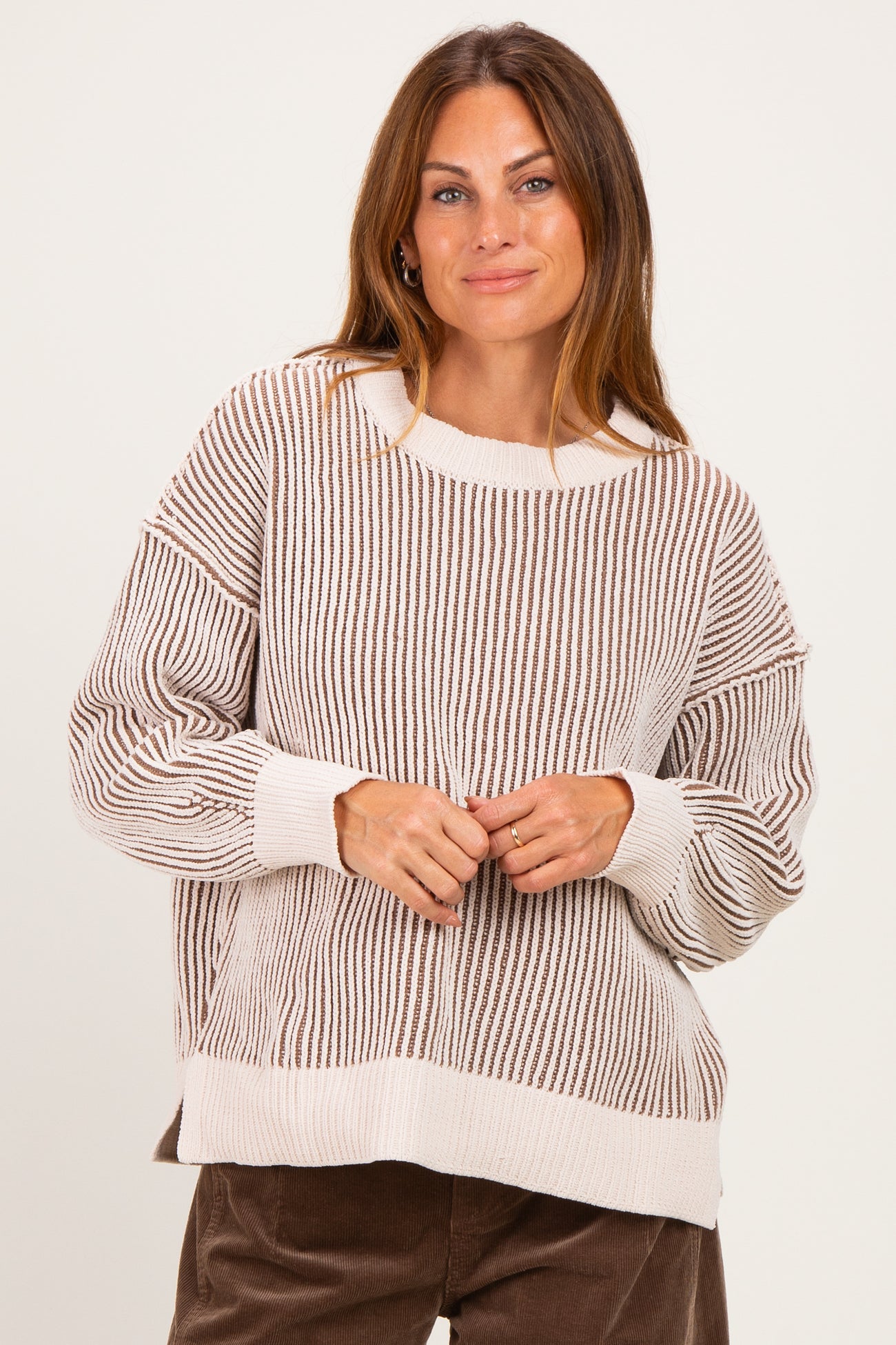woman wearing a beige and brown striped oversized sweater with long sleeves and a relaxed fit