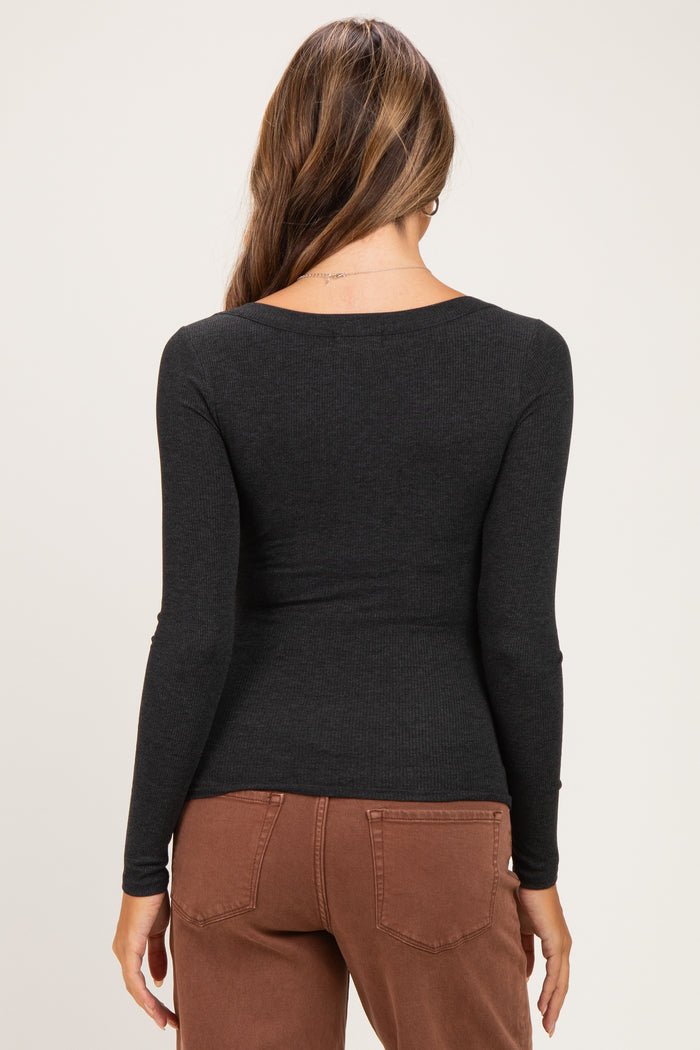 woman wearing a black long sleeve maternity top, viewed from the back, paired with brown pants